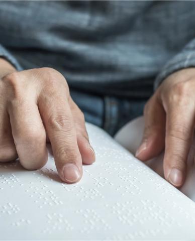 Manos de hombre leyendo braile